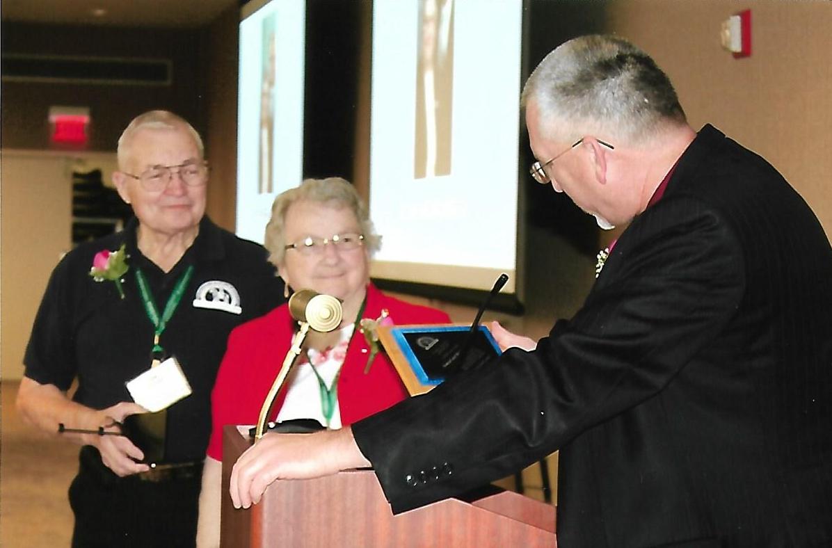 two people receiving an award at a conference